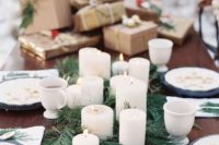 a winter tablescape with an evergrene runner, pillar candles and a stack of gifts on the table