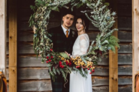 a winter wedding wreath with evergreens, greenery, berries and red blooms for decor and backdrops