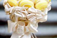 a yellow and white lollipop wedding bouquet with neutral ribbons and a bow with a brooch is a bold and catchy idea for a wedding
