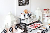 an elegant modern hot cocoa bar in blakc and white, with stands and jars, a sign and candle lanterns