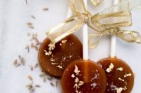 delicious caramel and gold lollipops with gold bows are amazing for your wedding dessert table or as wedding favors