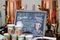 this hot chocolate bar is done with copper tanks, paper cups with tags and holders and a menu sign