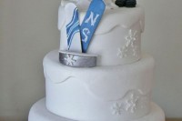 a white wedding cake with fun couple cake toppers and their snwoboards