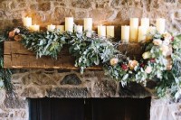 pillar candles on the mantel and lush greenery and blooms make the rough stone fireplace softer