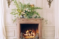 a working fireplace with a lush greenery and floral arrangement in the vase on the mantel looks very elegant