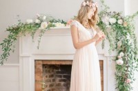 delicate fireplace styling with a greenery and pastel bloom garland plus bright and white candles on the floor