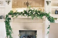 a greenery and white flower wedding garland with twigs is a stylish way to decorate the fireplace