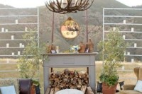 a faux fireplace with firewood, vine wrapped bottles, an antler chandelier for creating an outdoor lounge