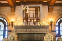 a fireplace styled with candles inside and on the mantel and neutral floral arrangements in bottles and vases