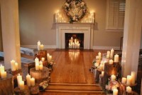 a faux fireplace with candles inside and on the mantel and a lush floral and greenery wreath over the mantel for a wedding ceremony