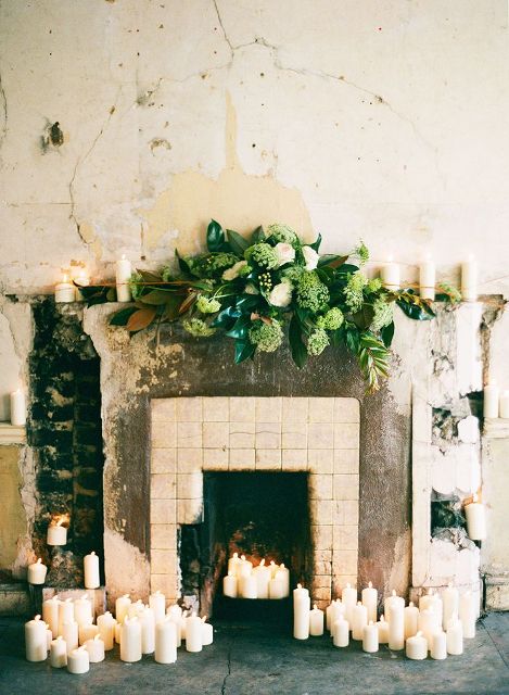 candles around the fireplace and on the mantel and lush greenery and white blooms look chic and lush