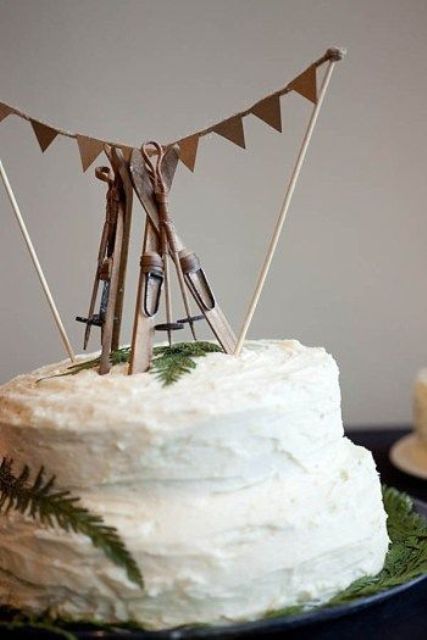 a textural buttercream wedding cake topped with greenery, skis and other ski stuff is a very beautiful and cozy dessert for a ski resort wedding