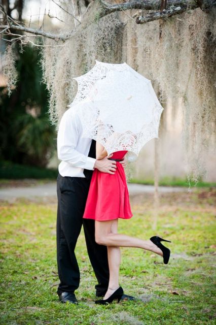 a red mini dress and a lace umbrella for pretty Valentine engagement pics with much romance and elegance