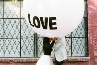 a romantic Valentine’s Day engagement pic with an oversized white balloon and a couple wearing a monochromatic outfit