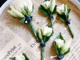 a newspaper tray with white bloom boutonnieres is a pretty detail for  avintage-inspired wedding and it looks very romantic