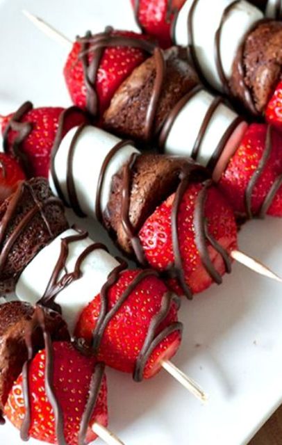 sweet Valentine wedding appetizers - skewers with marshmallows, chocolate cake and strawberries and chocolate glazing