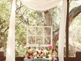 chic vintage wedding decor with a blue vintage dresser, bold and neutral blooms and greenery, a window frame and a neutral curtain over the space