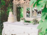 a white vintage dresser with a mirror, a crystal chandelier and blooms and a couple of delicious wedding cakes served is a refined idea