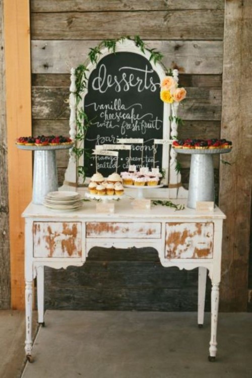 a vintage shabby chic dresser as a wedding sweets table, with a chalkboard menu, greenery and blooms, desserts on plates and tall stands