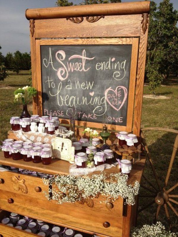 a stained vintage dresser used as a stand for wedding favors, with a chalkboard and blooms, with jam jars that are wedding favors