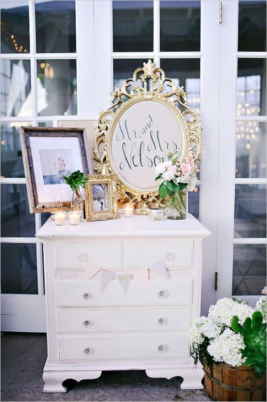 a neutral vintage dresser used for displaying wedding decor   wedding signs, candles, blooms and a photo   is a simple and cool idea