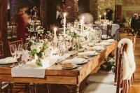 an industrial wedding venue with brick walls, pillars, hanging lights, candles, potted greenery and white blooms and comfy chairs