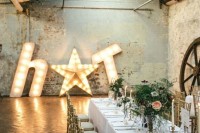 an industrial wedding venue with brick walls, exposed metal beams, marquee letters and a star and a long table with peachy blooms