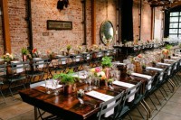 an industrial wedding venue with red brick walls, pipes, bright blooms and greenery and potted succulents for a bold look
