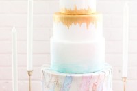a chic wedding cake with an ombre effect, an aqua and a gold touch and a tier featurign colorful world maps