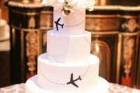 a white wedding cake decorated with black airplanes and fresh white blooms on top for a chic look
