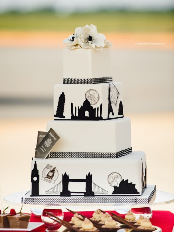 a stylish white and black wedding cake with London views and famous sights and fresh white blooms on top