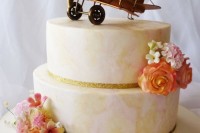a pastel abstract wedding cake with sugar blooms and a cool airplane topper