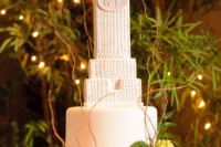 a chic white wedding cake topped with an Empire State Building and fresh blooms
