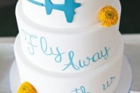 a white wedding cake with a plane and a wish plus some bright yellow blooms