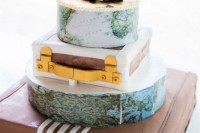 a whimsical wedding cak featuring map and suitcase tiers plus little cameras on top for a touch of fun
