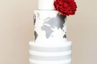 a white wedding cake with a striped and a map tier plus a bright red flower and a fun topper