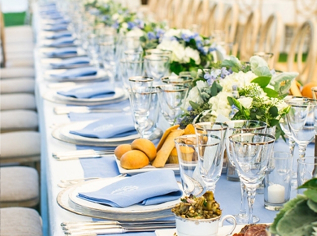 a beautiful serenity blue wedding tablescape with a serenity blue table runner and napkins, neutral and serenity blue blooms and greenery is very chic