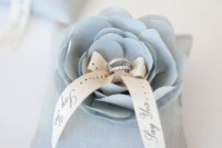 a creative wedding ring pillow with a serenity blue fabric flower that holds the rings