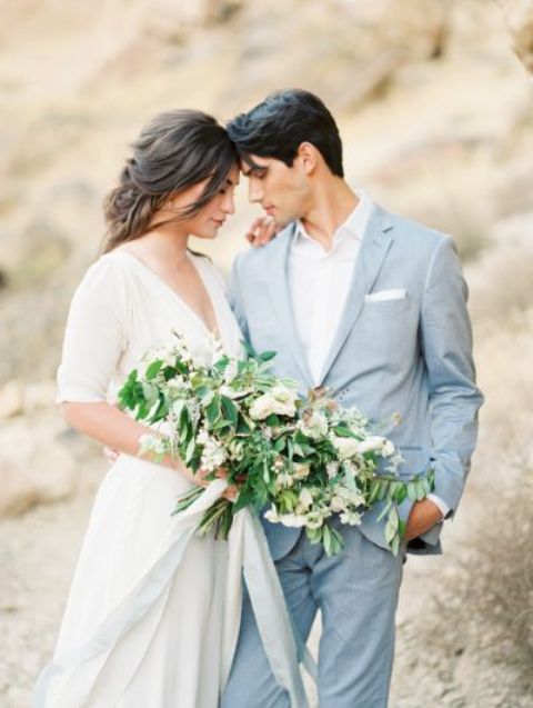 a groom wearing a serenity blue pantsuit, a white shirt and no tie - a perfect wedding outfit for a coastal wedding