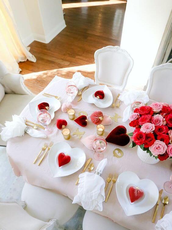 a beautiful Valentine engagement tablescape with blush linens, red and burgundy hearts and bold blooms