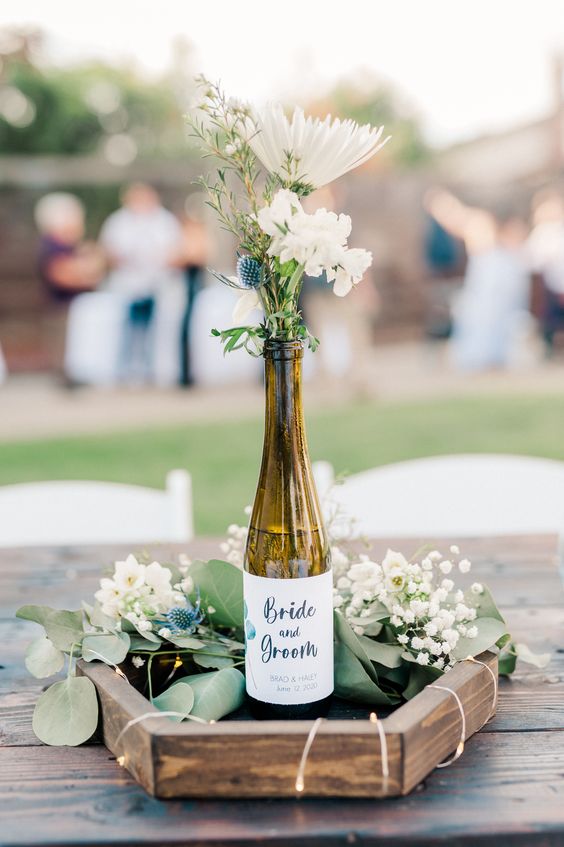 a beautiful and simple wedding centerpiece featuring custom wine bottle labels, fresh florals, and handmade hexagon rounds