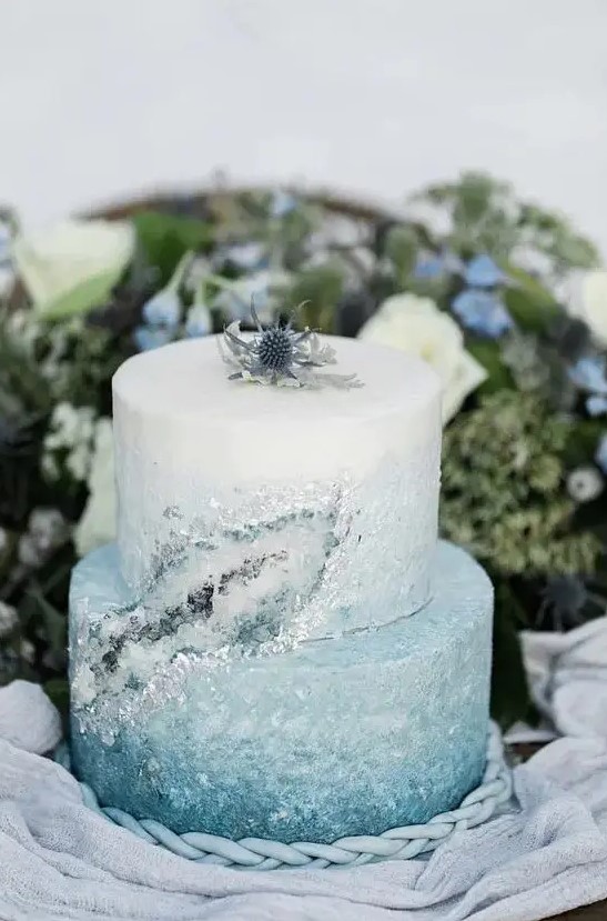 a beautiful ombre serenity blue winter wedding cake with crystals and a thistle on top the cake is lovely