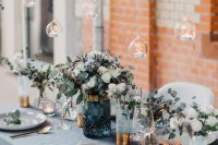 a beautiful serenity blue wedding tablescape with a serenity blue tablecloth and vases with white blooms and candles, candles over the table