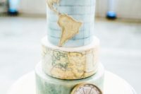 a beautiful travel-themed wedding cake with map and ombre layers, fresh blooms and a compass for decor