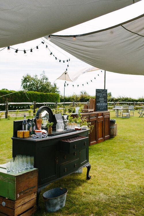 a black vintage dresser styled as a wedding drink station, with greener and a mirror and lots of drinks is a lovely idea