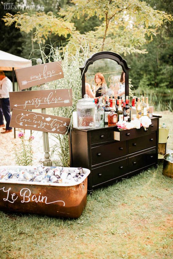 a black vintage dresser with a mirror styled as a drink bar and blooms in a drawer is a lovely idea for a vintage wedding