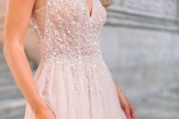 a blush wedding dress with embellishments, a deep neckline and cutout sides is a chic and romantic option to try