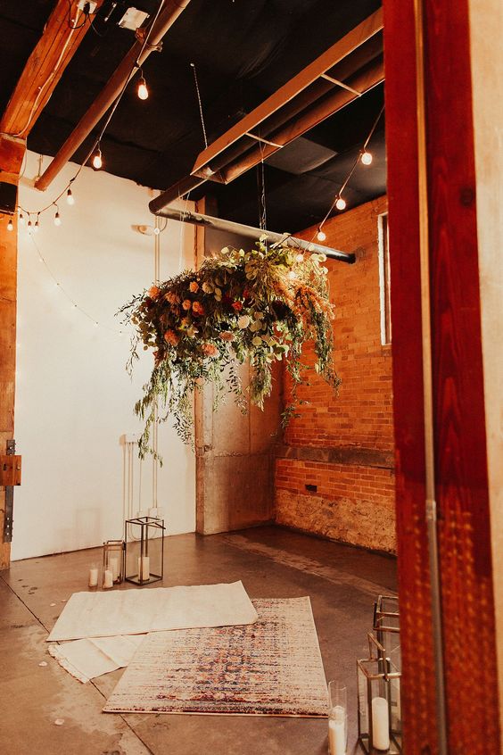 a boho industrial wedding space with lush blooms, greenery, boho rugs and candles