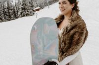 a bride dressed for riding and showing off her gorgeous snowboard for the wedding