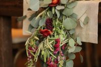 a burlap table runner, a greenery runner with red and burgundy blooms and candles for decorating a ski resort reception